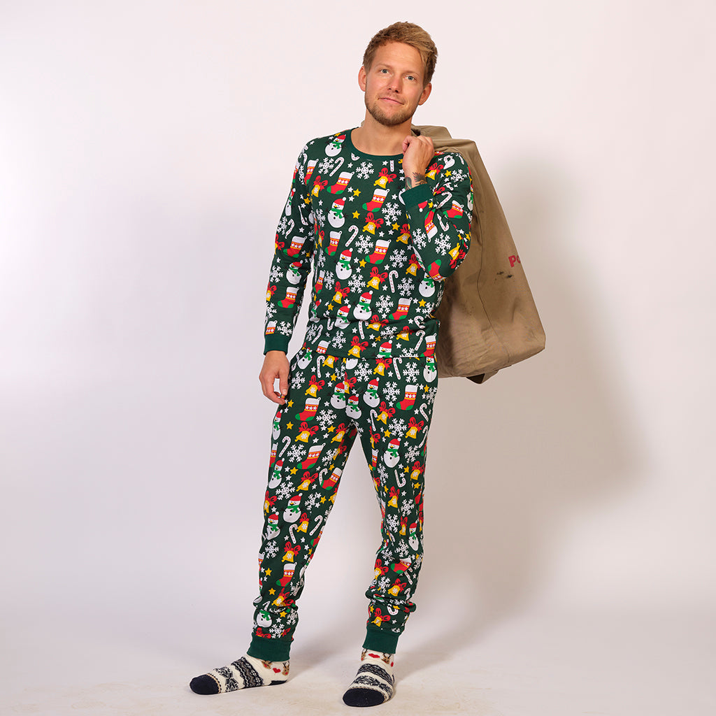 En mand står med en julesæk iført en grøn julepyjamas.